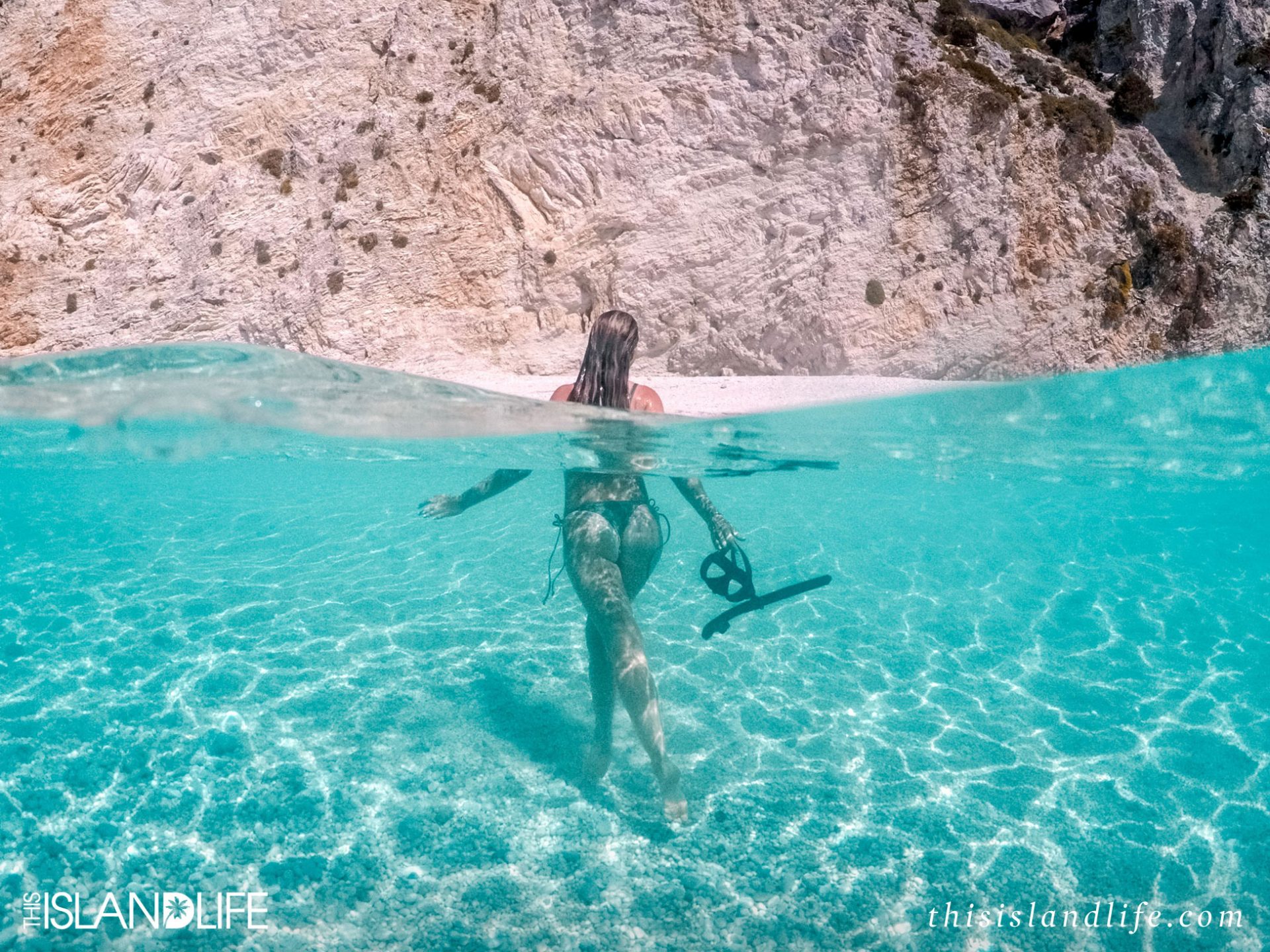 Underwater photo of girl jumping off boat at secret beach on Ithaca Island