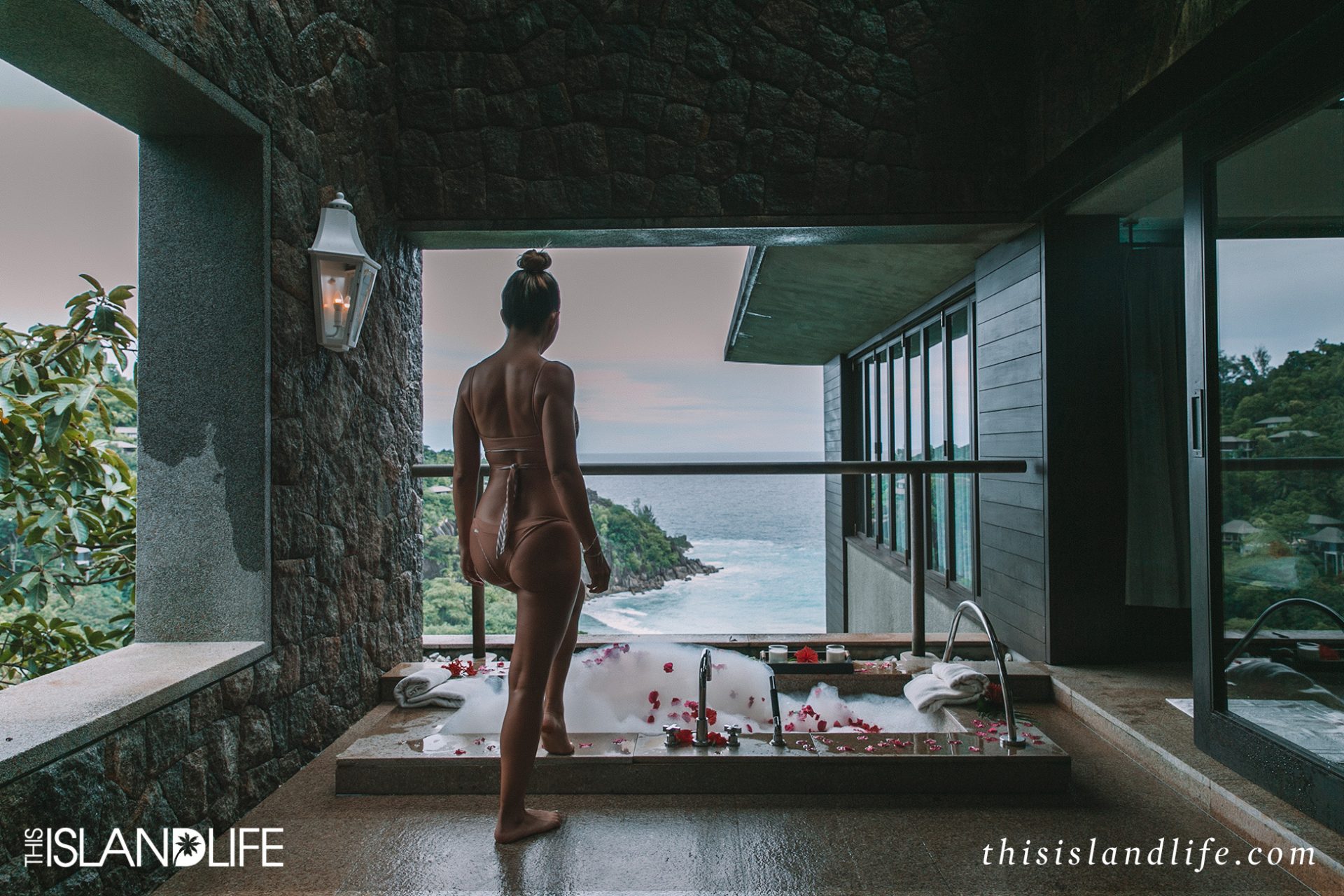 Woman getting into bubble bath with ocean views in the Seychelles 