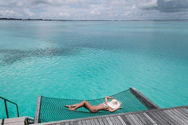 Girl in bikini on net at an overwater villa - Shangri-La's Villingili, Maldives