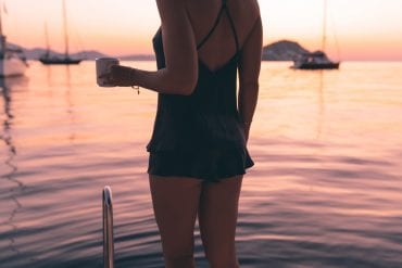 Girl in silk lingerie on sailing yacht at sunrise
